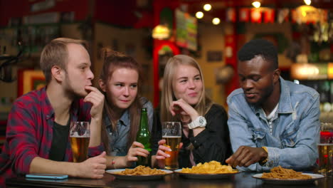 Eine-Multiethnische-Gruppe-Von-Sieben-Befreundeten-Männern-Und-Frauen,-Die-Lachen,-Bier-Trinken-Und-Toasts-Ausbringen.
